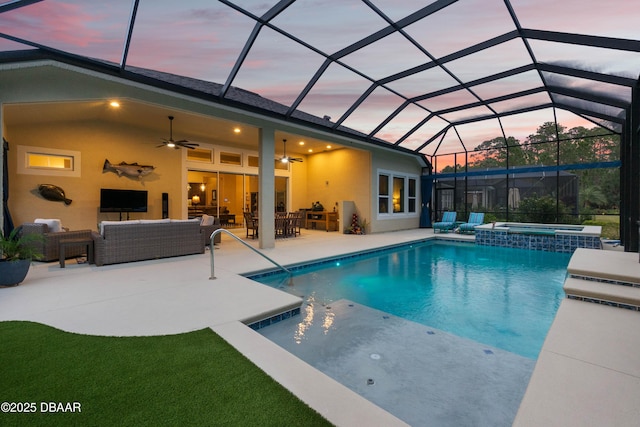 pool at dusk featuring an in ground hot tub, ceiling fan, glass enclosure, an outdoor living space, and a patio area