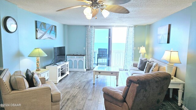 living room featuring wood-type flooring, ceiling fan, and a textured ceiling