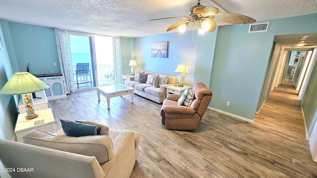 living room with ceiling fan, a textured ceiling, and light hardwood / wood-style flooring