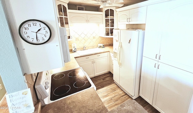 kitchen with cooktop, sink, ceiling fan, white fridge with ice dispenser, and light wood-type flooring