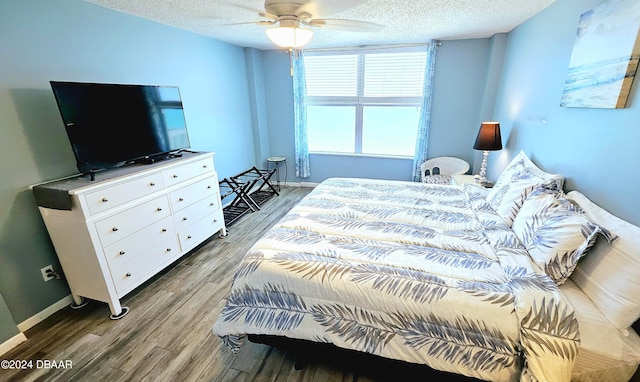 bedroom featuring hardwood / wood-style floors, ceiling fan, and a textured ceiling