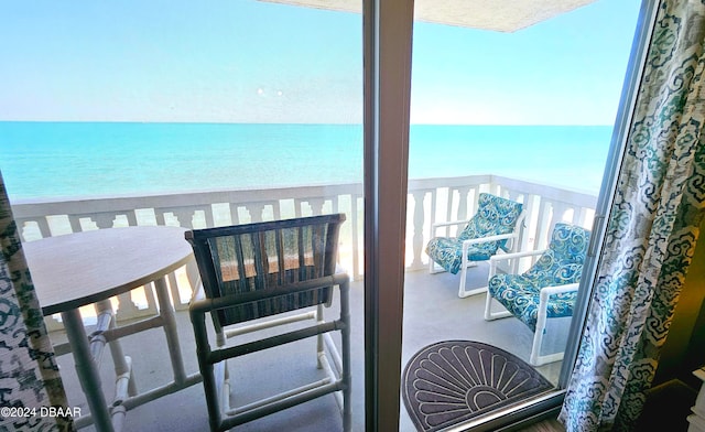 balcony with a water view and a view of the beach