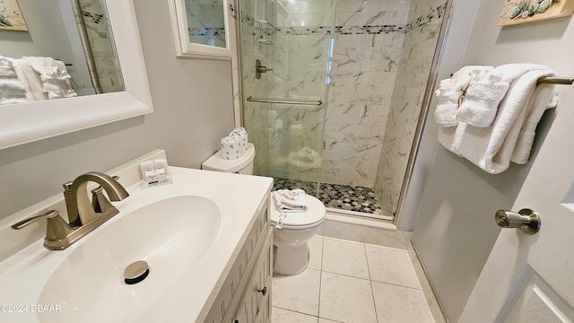 bathroom with toilet, tile patterned floors, vanity, and a shower with door