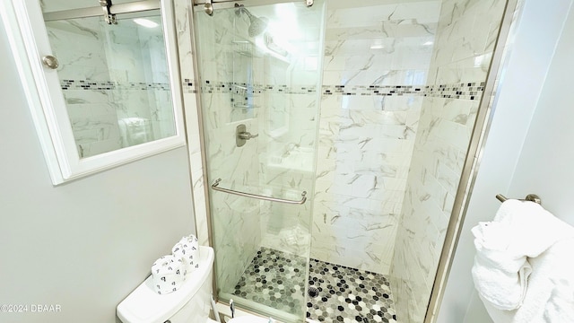 bathroom featuring a shower with door and toilet