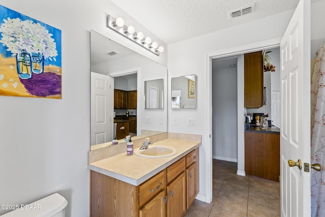 bathroom with tile patterned flooring, visible vents, a textured ceiling, and toilet