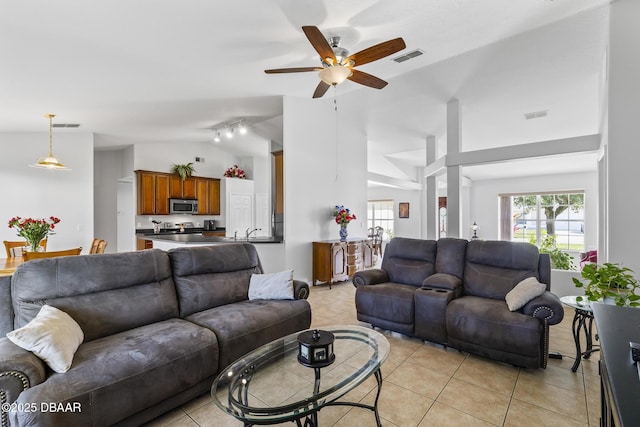 living area featuring light tile patterned floors, visible vents, and vaulted ceiling