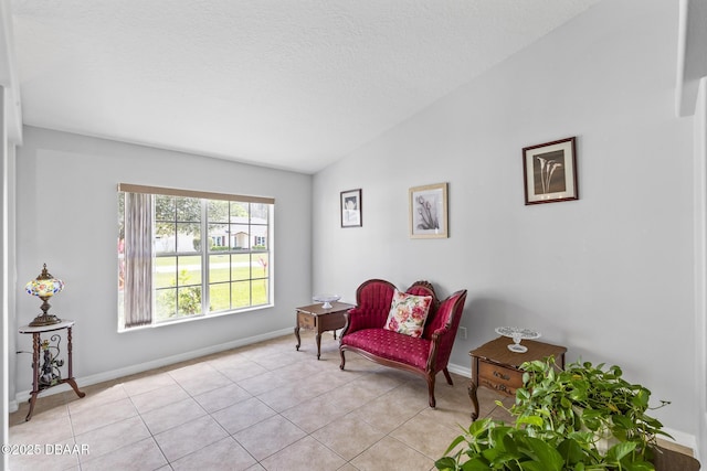 sitting room with lofted ceiling, a textured ceiling, baseboards, and light tile patterned floors