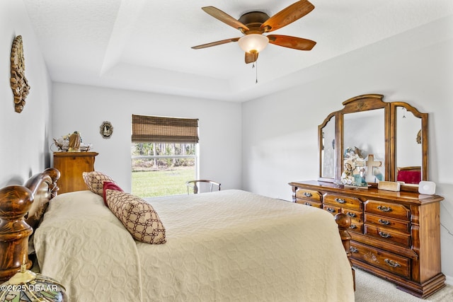 bedroom with carpet floors, a raised ceiling, and a ceiling fan