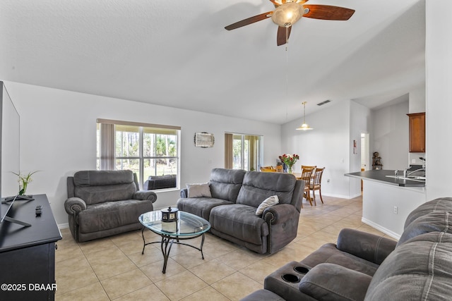 living area featuring light tile patterned floors, baseboards, visible vents, lofted ceiling, and ceiling fan