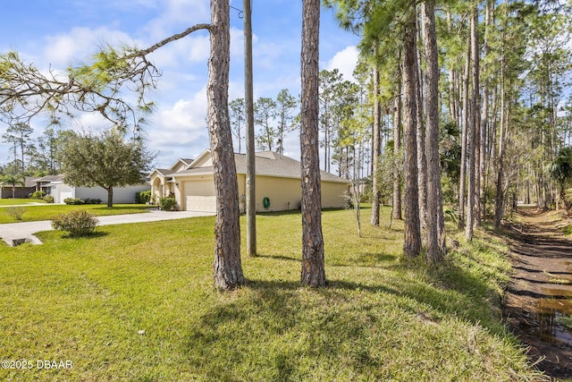 view of front of property with a garage, driveway, a front lawn, and stucco siding