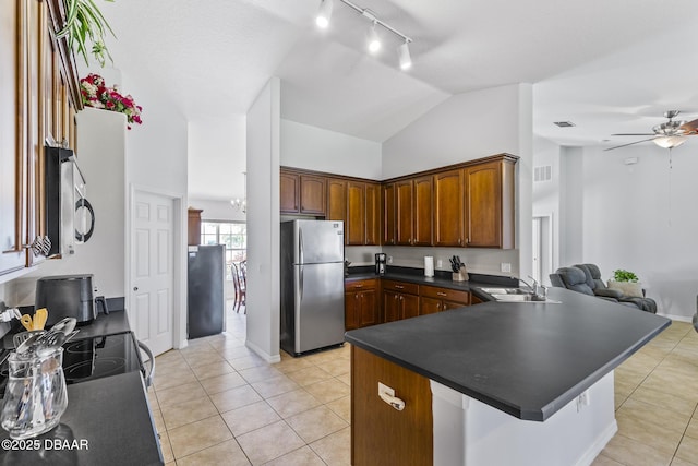 kitchen with light tile patterned floors, a ceiling fan, dark countertops, appliances with stainless steel finishes, and a sink