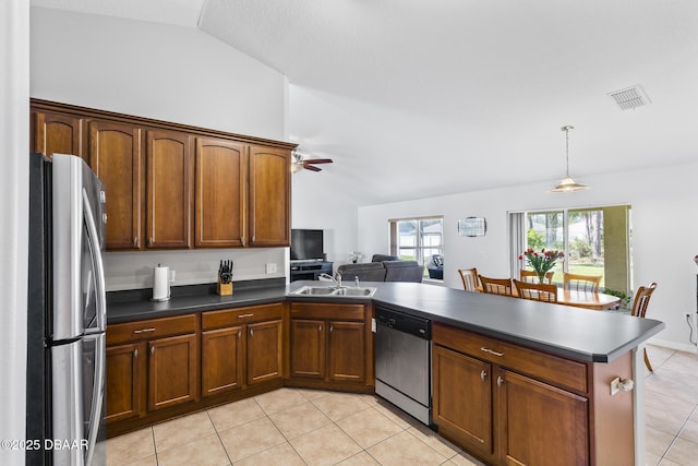 kitchen with light tile patterned floors, dark countertops, appliances with stainless steel finishes, vaulted ceiling, and a sink