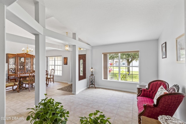 living area with a chandelier, lofted ceiling, a textured ceiling, and light tile patterned floors