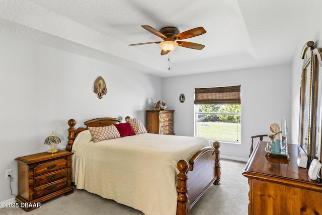 bedroom featuring carpet, a textured ceiling, a tray ceiling, and baseboards