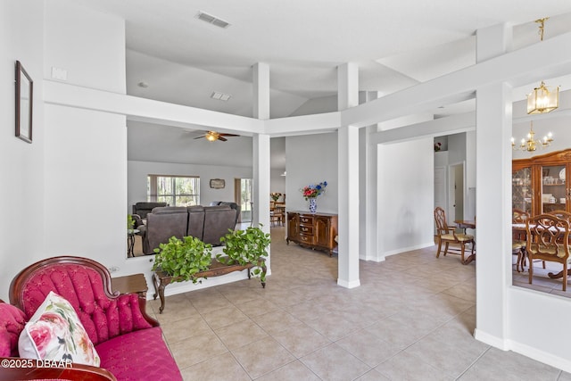 living area with light tile patterned floors, lofted ceiling, visible vents, baseboards, and ceiling fan with notable chandelier