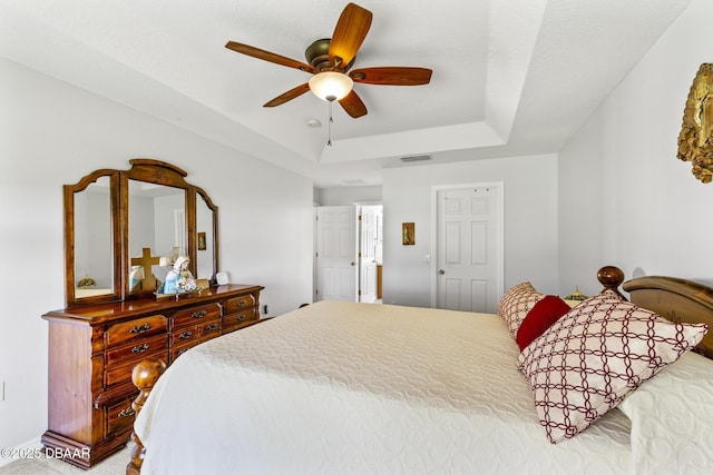 bedroom featuring ceiling fan, a tray ceiling, and visible vents