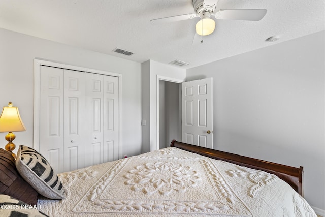 bedroom with a ceiling fan, a textured ceiling, visible vents, and a closet