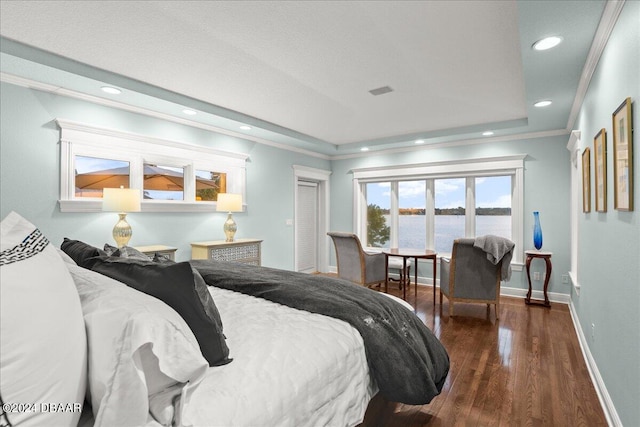 bedroom featuring dark hardwood / wood-style floors, a closet, a water view, and crown molding