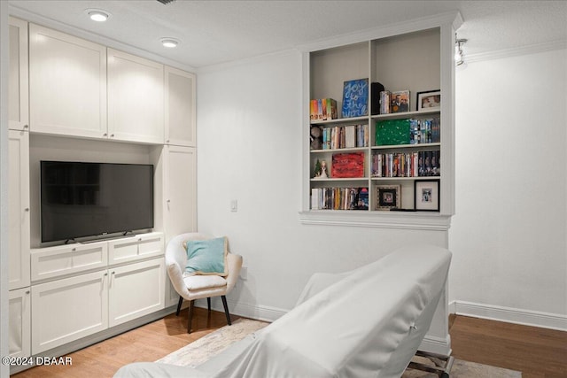 living area with a textured ceiling, crown molding, and light hardwood / wood-style flooring