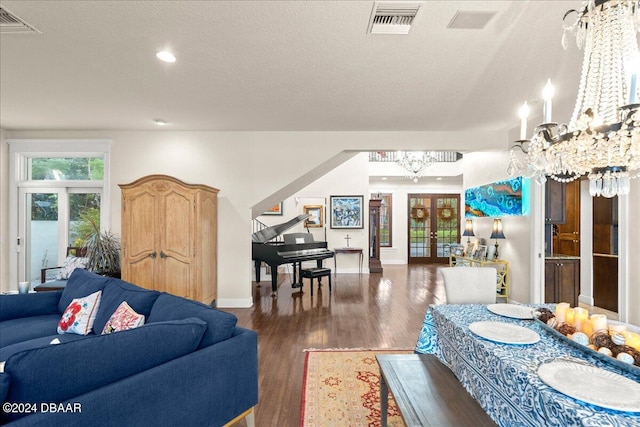 living room with french doors, a notable chandelier, dark hardwood / wood-style floors, and a textured ceiling