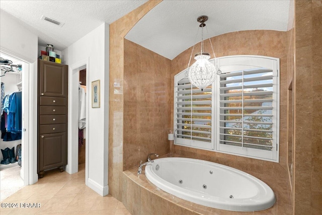 bathroom featuring tiled tub, a textured ceiling, a notable chandelier, vaulted ceiling, and tile patterned flooring