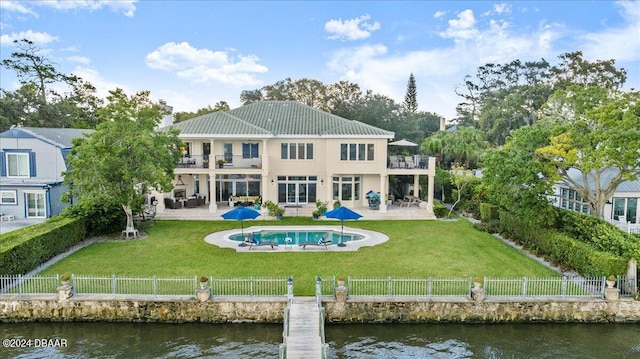 back of house featuring a yard, a fenced in pool, a patio, and a water view