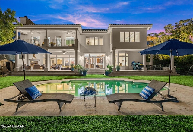 pool at dusk with an outdoor hangout area, a yard, and a patio area