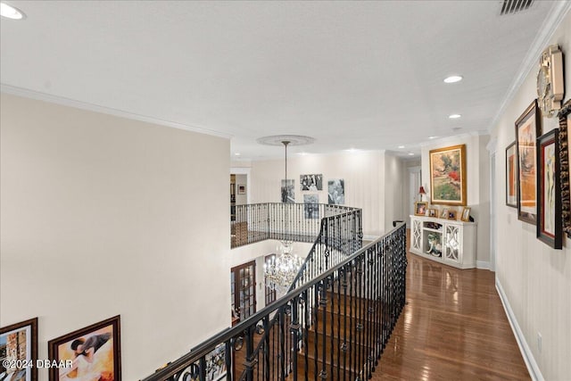 corridor featuring wood-type flooring, a notable chandelier, and crown molding