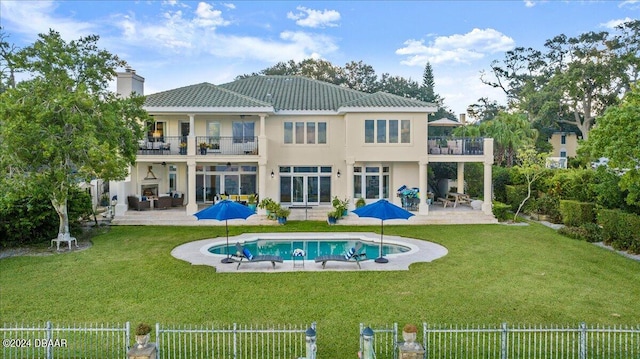 rear view of house with a balcony, a fenced in pool, a yard, and a patio area