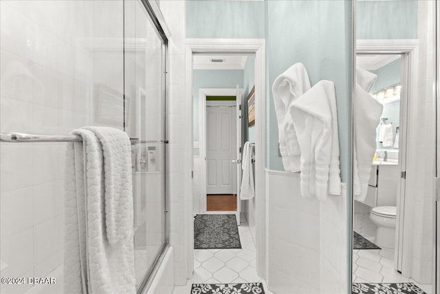 bathroom featuring toilet, bath / shower combo with glass door, tile patterned flooring, and ornamental molding