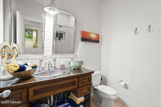 bathroom with tasteful backsplash, tile walls, vanity, tile patterned flooring, and toilet