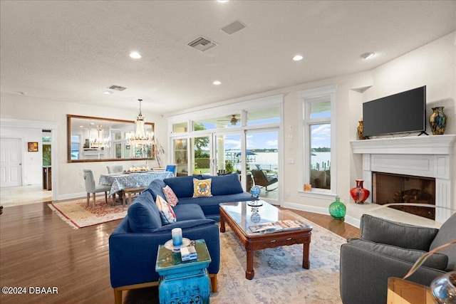 living room featuring a textured ceiling, hardwood / wood-style flooring, and an inviting chandelier