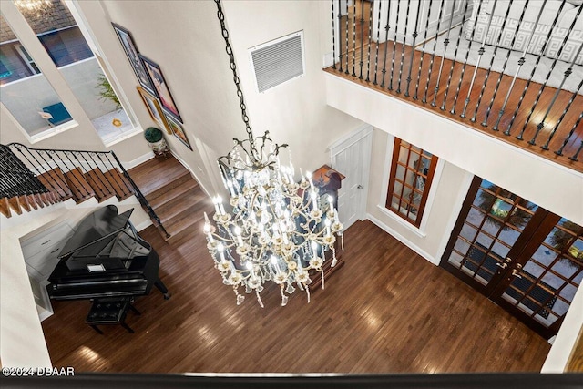 living room featuring hardwood / wood-style floors, a high ceiling, an inviting chandelier, and french doors