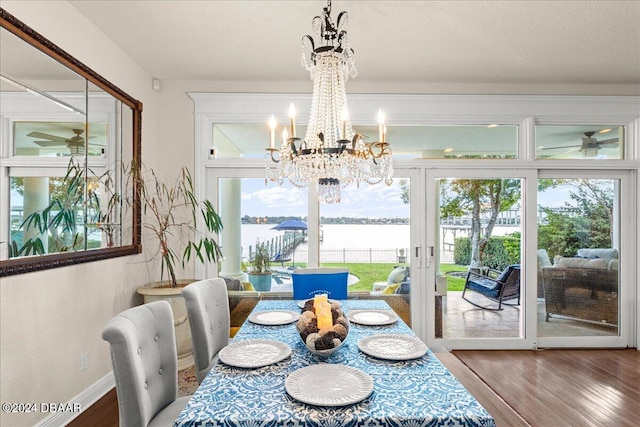 dining area with an inviting chandelier, plenty of natural light, a water view, and wood-type flooring