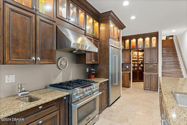 kitchen featuring high quality appliances, sink, and light stone counters