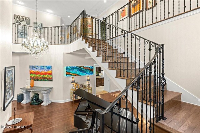 stairs featuring hardwood / wood-style flooring, a towering ceiling, and crown molding