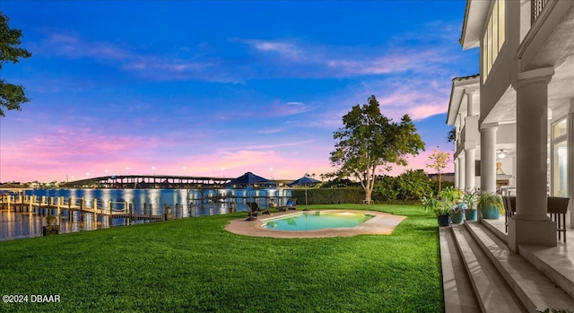 pool at dusk with a yard and a water view