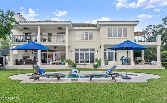 back of property with ceiling fan, a balcony, a yard, and a patio area