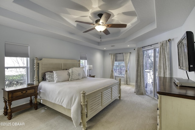 carpeted bedroom featuring a raised ceiling and ceiling fan