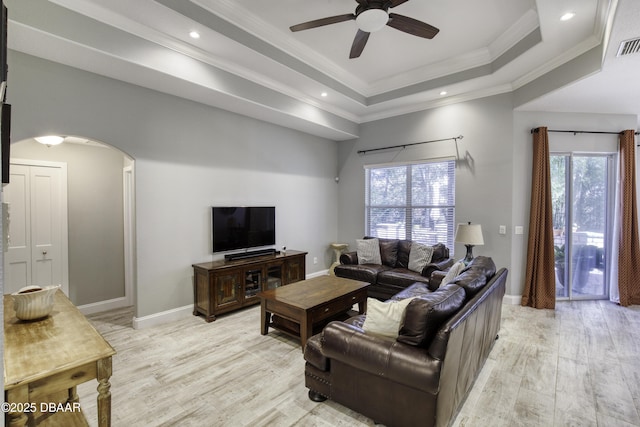 living room with a tray ceiling, ceiling fan, light hardwood / wood-style floors, and ornamental molding