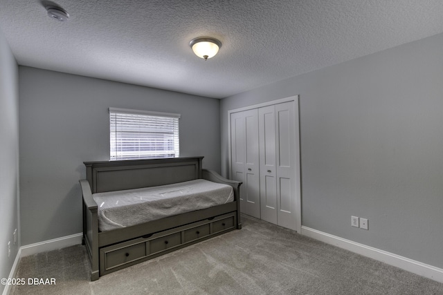 carpeted bedroom with a textured ceiling and a closet