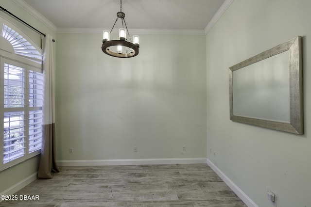 spare room with light wood-type flooring, ornamental molding, and an inviting chandelier