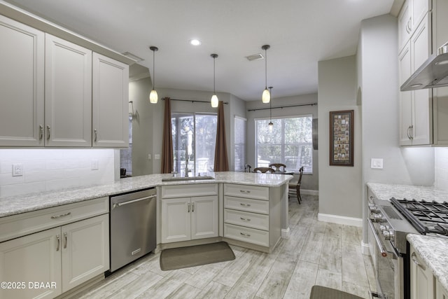 kitchen with kitchen peninsula, stainless steel appliances, hanging light fixtures, and tasteful backsplash