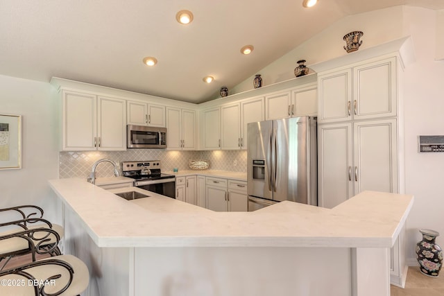 7 Fernery Trl, Ormond Beach, FL 32174 - kitchen featuring appliances with stainless steel finishes, lofted ceiling, light countertops, decorative backsplash, and a peninsula