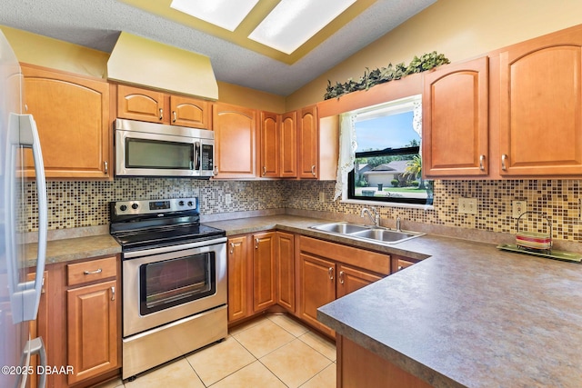 104 Herring Gull Ct, Daytona Beach, FL 32119 - kitchen with appliances with stainless steel finishes, lofted ceiling, decorative backsplash, light tile patterned floors, and brown cabinets