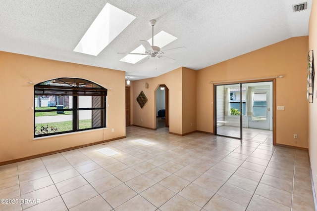 104 Herring Gull Ct, Daytona Beach, FL 32119 - spare room featuring vaulted ceiling, a skylight, light tile patterned floors, ceiling fan, and arched walkways