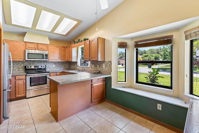 104 Herring Gull Ct, Daytona Beach, FL 32119 - kitchen with stainless steel appliances, vaulted ceiling, a peninsula, backsplash, and light tile patterned floors