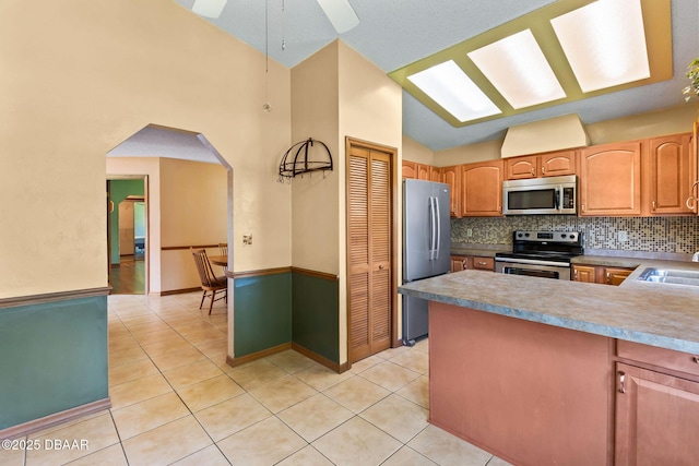 104 Herring Gull Ct, Daytona Beach, FL 32119 - kitchen with appliances with stainless steel finishes, light tile patterned flooring, vaulted ceiling, arched walkways, and tasteful backsplash