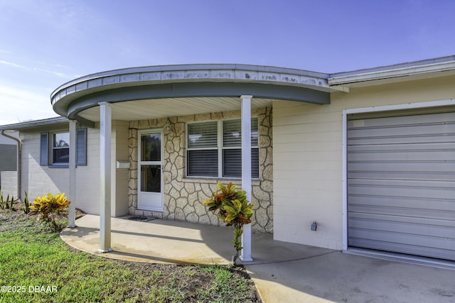 34 Kathy Dr, Ormond Beach, FL 32176 - entrance to property featuring concrete block siding, a garage, and covered porch