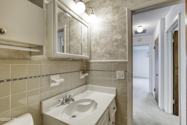 34 Kathy Dr, Ormond Beach, FL 32176 - bathroom with wallpapered walls, vanity, tile walls, toilet, and a wainscoted wall